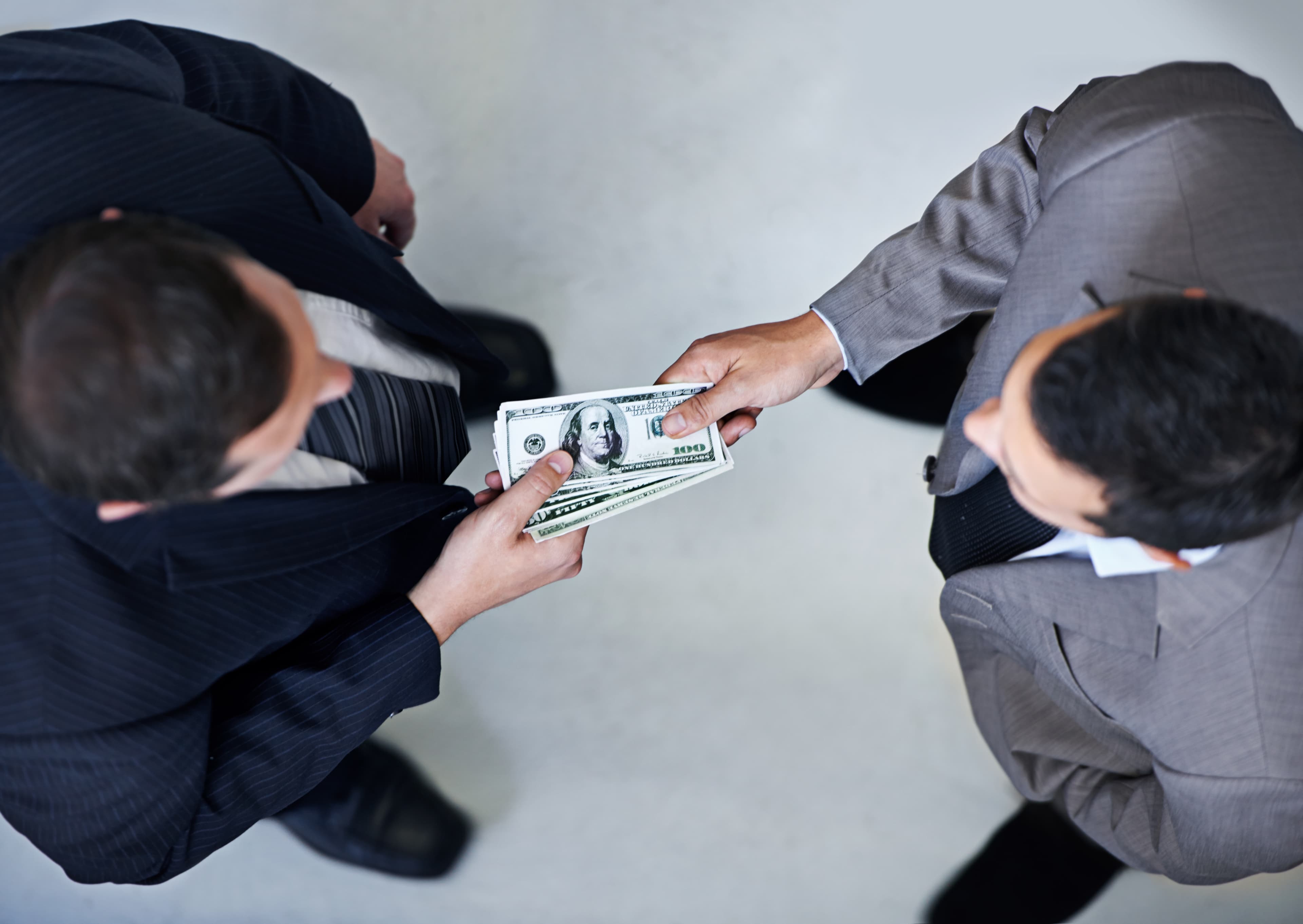 Intercambio de dinero entre dos adultos representando negociación salarial